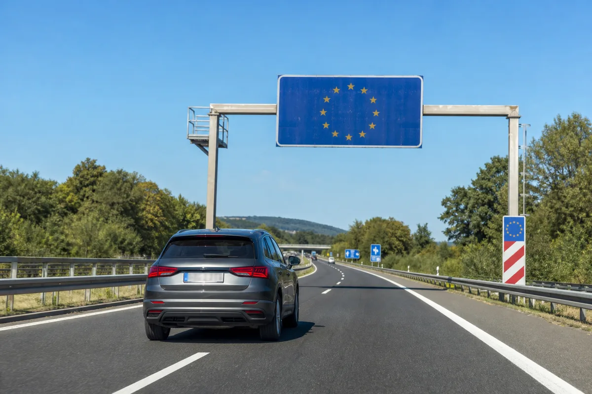 Voiture immatriculée en France franchissant un panneau frontière européenne sur autoroute